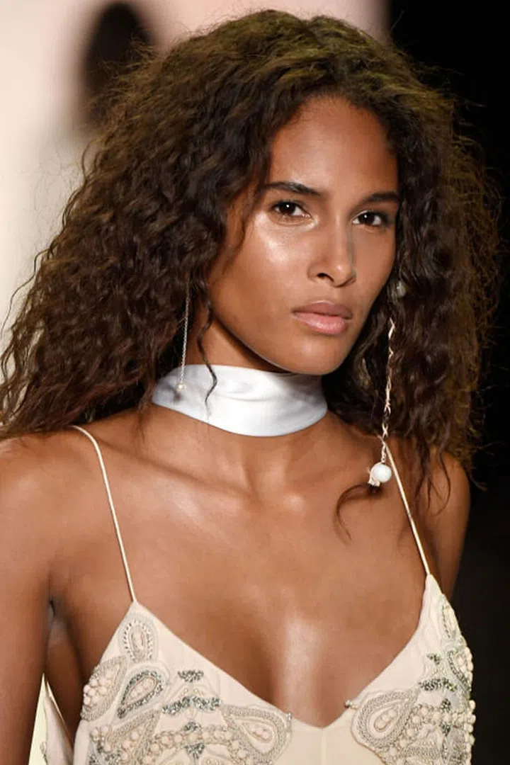 The Look: Hidden Braids
How-To: Any beauty look that comes with a hidden surprise is a winner in our book. Backstage at Jonathan Simkhai, hairstylist Thomas Osborn hid a couple of woven, beaded braids within a fuzzy, textured style (He was dubbing it "desert drifter"). The one or two small braids were placed right near the left ear; each was adorned with a few colorful beads and string that complemented shades seen in the collection. The braids were a little hard to see (editors and photographers had to keep asking the models to pull them out for pictures)—but that was precisely the point. It was a subtle, quiet beauty statement that still made a big impact. Photo: IMAXTREE