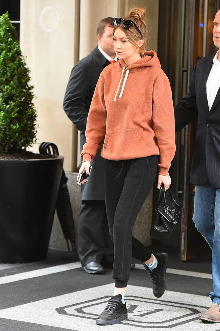 Hadid stepped out in off-duty athleisure, pairing a muted orange sweatshirt by Kith NYC with black joggers and sneakers, plus a Versace bag and Karen Walker sunnies. Photo: Splash