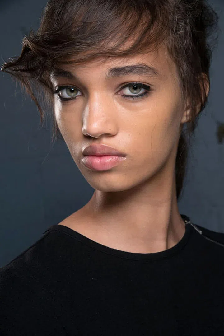 The runway at 3.1 Phillip Lim was scattered with crushed flowers and dirt. It was meant to look like a dance had happened there the night before, a sort of Western-inspired high school prom. In beauty, that theme translated to sharp black eyeliner and a deconstructed, '60s- inspired low ponytail. Makeup artists traced a black liquid NARS eyeliner all around the eye, from the top to bottom lid. After filling in the waterlines with a kohl pencil, they used a Q-tip dipped in micellar water to wipe away the liner just at the edges of the eye. The effect was a sort of play on negative space, as if the girls had been dancing all night and their eyeliner just stayed put.