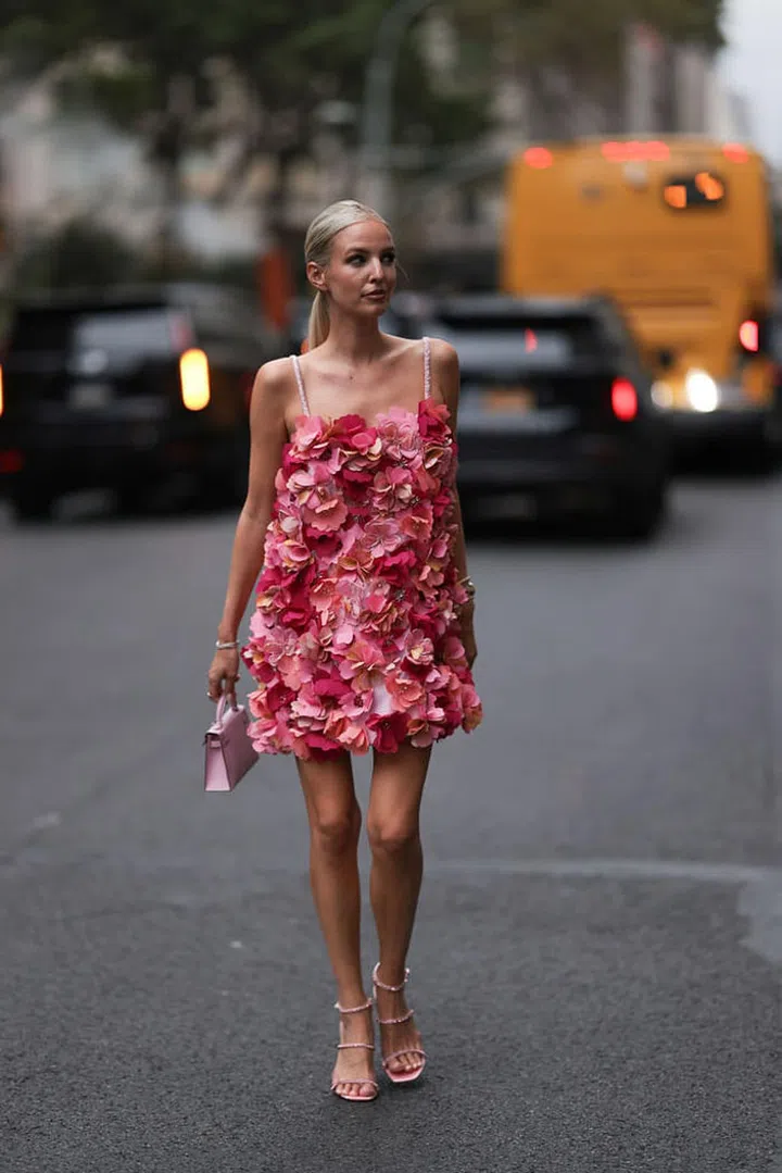 NEW YORK - SEPTEMBER 09: Leonie Hanne is seen wearing a mini dress with spaghetti straps and sewed on flowers in different shades of pink, several bracelets, golden rings, a golden/silver watch, the mini Kelly Bag from Hermès in lilac leather and pink strap sandals with rhinestones outside bevor the PatBo Show on September 09, 2023 in New York City. (Photo by Jeremy Moeller/Getty Images)
