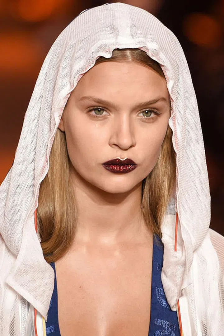 There was a palpable frenzy in the air backstage at DKNY. To describe it accurately would be to say it was like your Instagram feed come to life: buzzy models like Bella Hadid and Jasmine Sanders slinking about in full-on glittery lips. If you follow Pat McGrath on Instagram, you've no doubt seen this look before (Her Lust 004 Lipstick Kit in Bloodwine was on display). But just because the look wasn't new didn't mean it wasn't perfect for the DKNY collection. For the show, McGrath created what she called a  "crescendo of glitter." The first models on the runway only had a simple, dark lip. More and more glitter was added until the last few models walked in the Pat McGrath trademark sparkle. She left the skin fresh and natural; the eyes unadorned. When the models slipped into the collection's slinky dresses and popped up their hoods, the only visible beauty moment was the intense reflection of the lips. McGrath called it urban glamour; we call it Instagram bait.