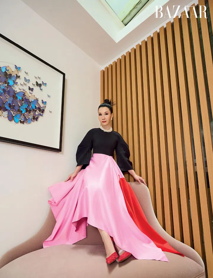Perched atop a plush Christopher Guy couch, Harrison is dressed in a Solace London dress, Valentino pumps, CELINE earrings, and pearl necklaces from Tiffany & Co. that were a college graduation gift from her parents.