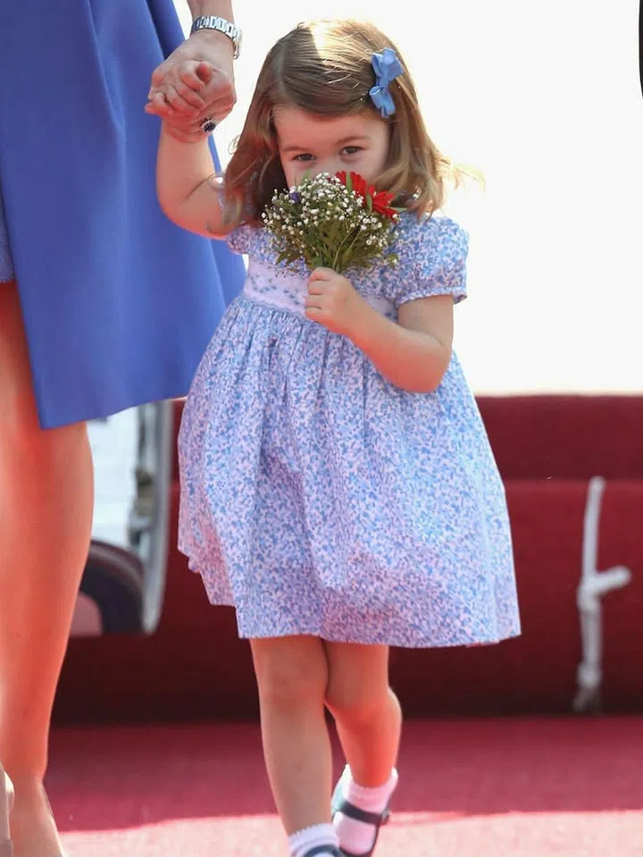 Princess Charlotte of Cambridge smells a bundle of flowers she was presented with during an official visit to Germany.