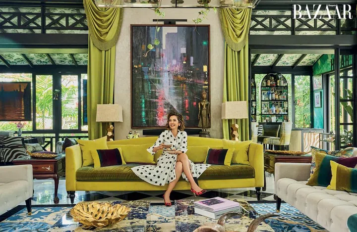 Hunt, wearing her own Carolina Herrera dress and pumps, and Tiffany & Co. necklace, enjoys a quiet moment in her formal dining room which has a custom-made carpet and statement chartreuse couch that pairs with her drapes. 
