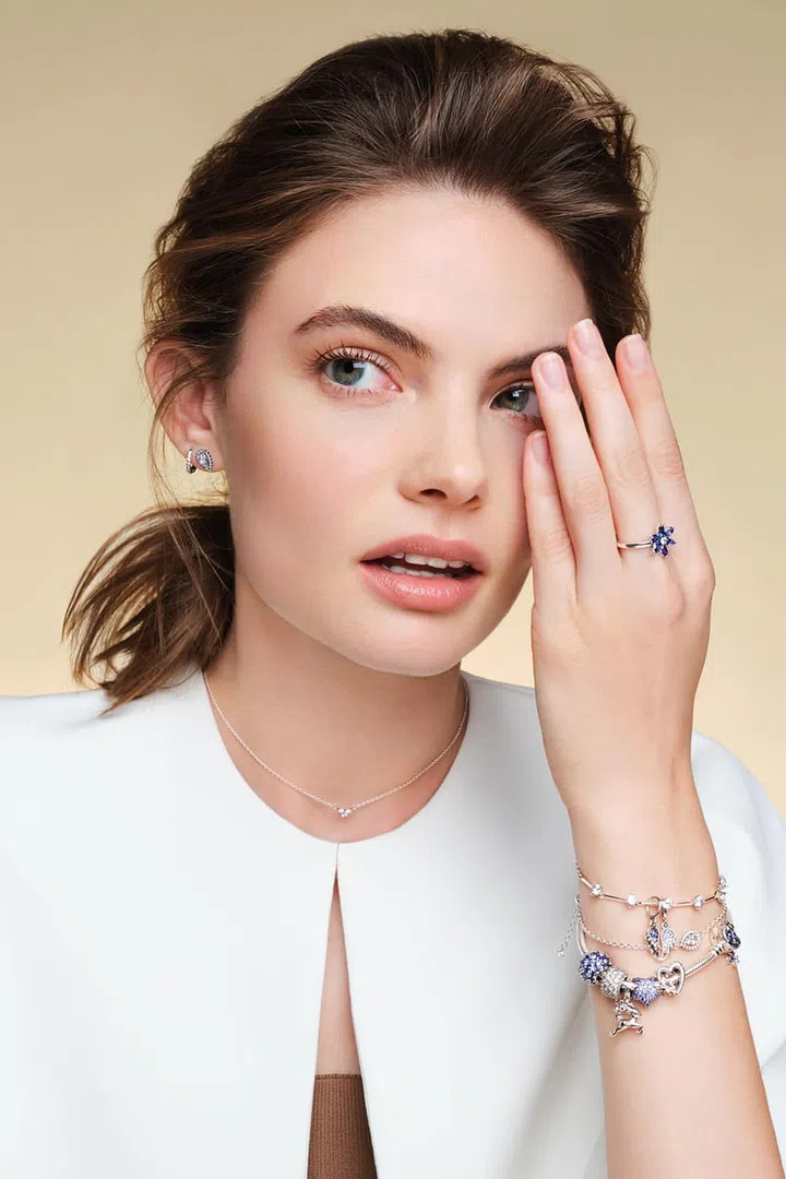 From top: Sterling silver and crystal Timeless Sparkling Huggie Hoop earrings; Sparkling Pear Halo Stud earrings; Sparkling Herbarium Cluster ring, Triple Stone Heart Collier necklace; Sparkling Bars bracelet with Moments Splittable Angel Wings Dangle charm; Sparkling Pear Halo Chain bracelet; Moments Sparkling Moon Clasp Snake Chain bracelet with Sparkling Pavé Round Blue Charm, Sparkling Pavé Triple Row charm, Magical Christmas Reindeer Dangle charm, Bold Pavé Star charm and Openwork Family Heart charm and Star charm, Pandora. Jacket and ribbed tank top, In Good Company