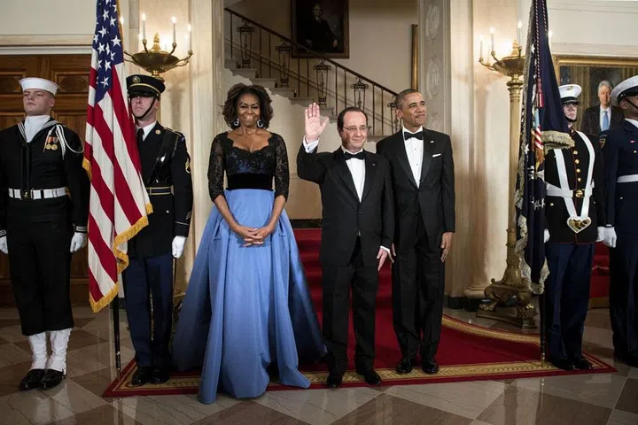 The Obamas pose with French President Francois Hollande in front of the Grand Staircase in the White House.