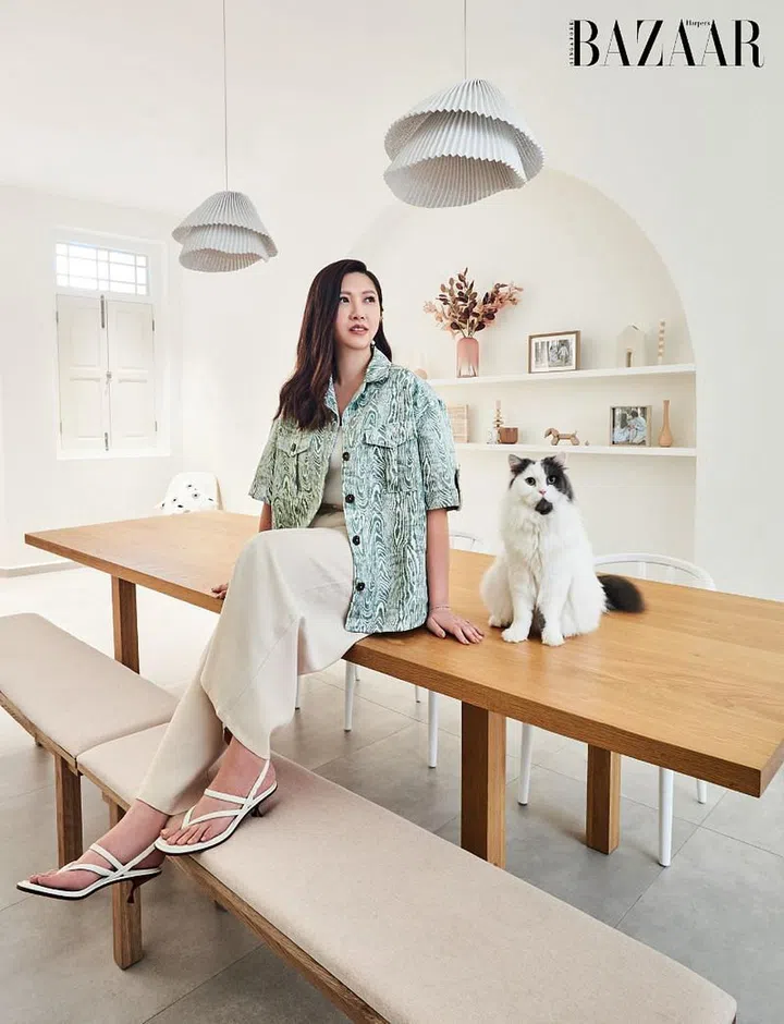 Wong, decked in her own C/MEO Collective shirt, top, AforArcade trousers, Dior earrings, The Canary Diamond Co. bracelet, and ring, worn with heeled sandals from Tod’s, perched atop the custom Till Kautz dining table with Dumpling.