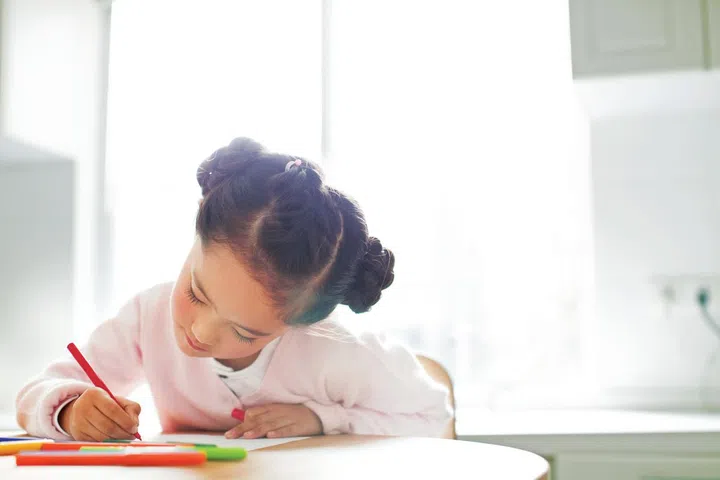Portrait of a girl coloring in with pens.