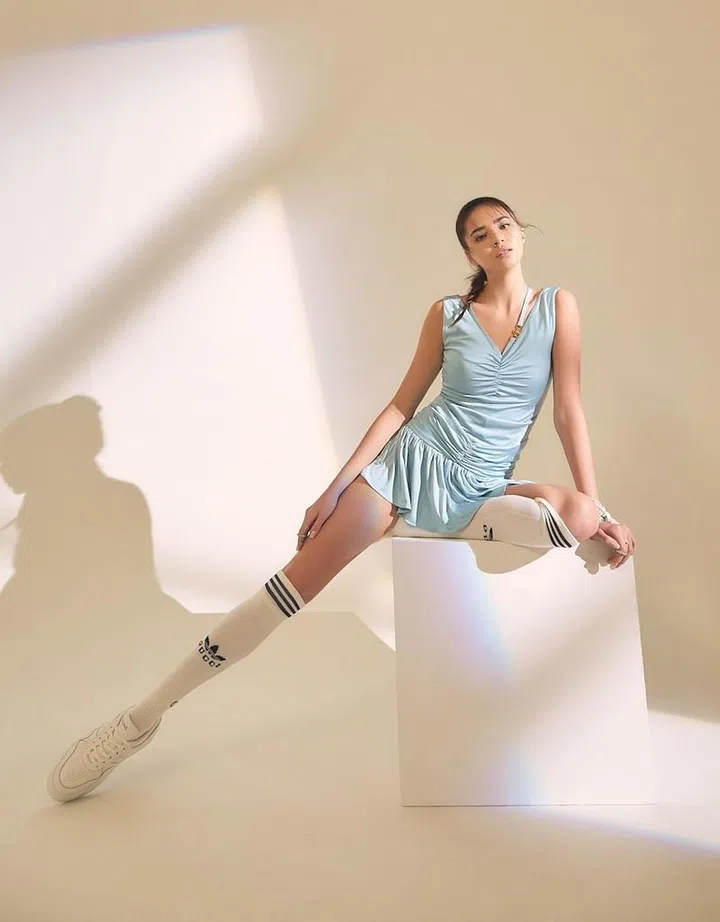Socks, from adidas x Gucci. Dress, from Versace. Ear cuffs; scarf (around wrist), both from Hermès. Rings, from Givenchy. Sneaker, from CELINE. (Photo: Veronica Tay)