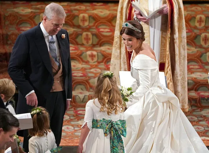 Princess Eugenie hands her bouquet off to one of her bridesmaids.