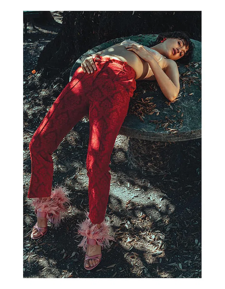 Jacquard pants; metal earring, Givenchy. Silk-blend sandals with ostrich feathers, Prada. Lace bra, stylist’s own