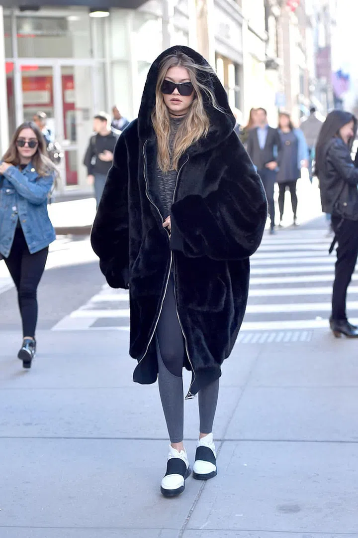Hadid looked cozy hitting the streets of New York, topping her black + white athleisure look with an oversized furry coat. Photo: Getty