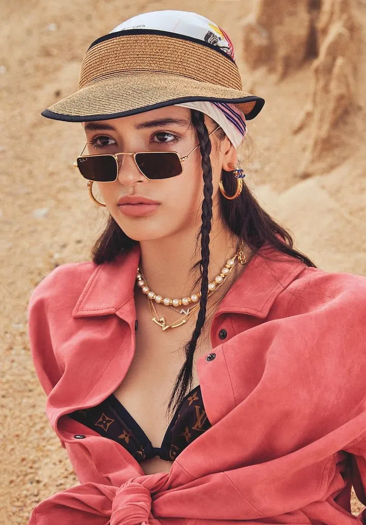 Visor, Roger Vivier. Shirt, Longchamp. Bikini top; necklaces, Louis Vuitton. Scarf (around head), Hermès. Sunglasses, Ray-Ban. Earrings, Chanel. Pearl necklace, Valentino. Necklace, model’s own. (Photo:  Phyllicia Wang)