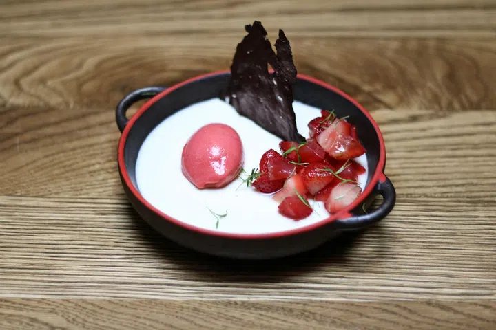 A light almond panna cotta served with minty
poached strawberries, fresh, tangy sorbet, and
a chocolate tuille

Photo: Courtesy of Open Door Policy