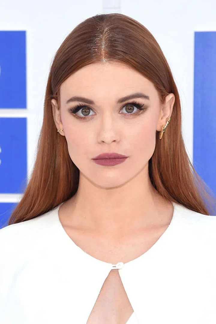 The Teen Wolf star accents her middle part with gold glitter while donning a moody purple lip. 