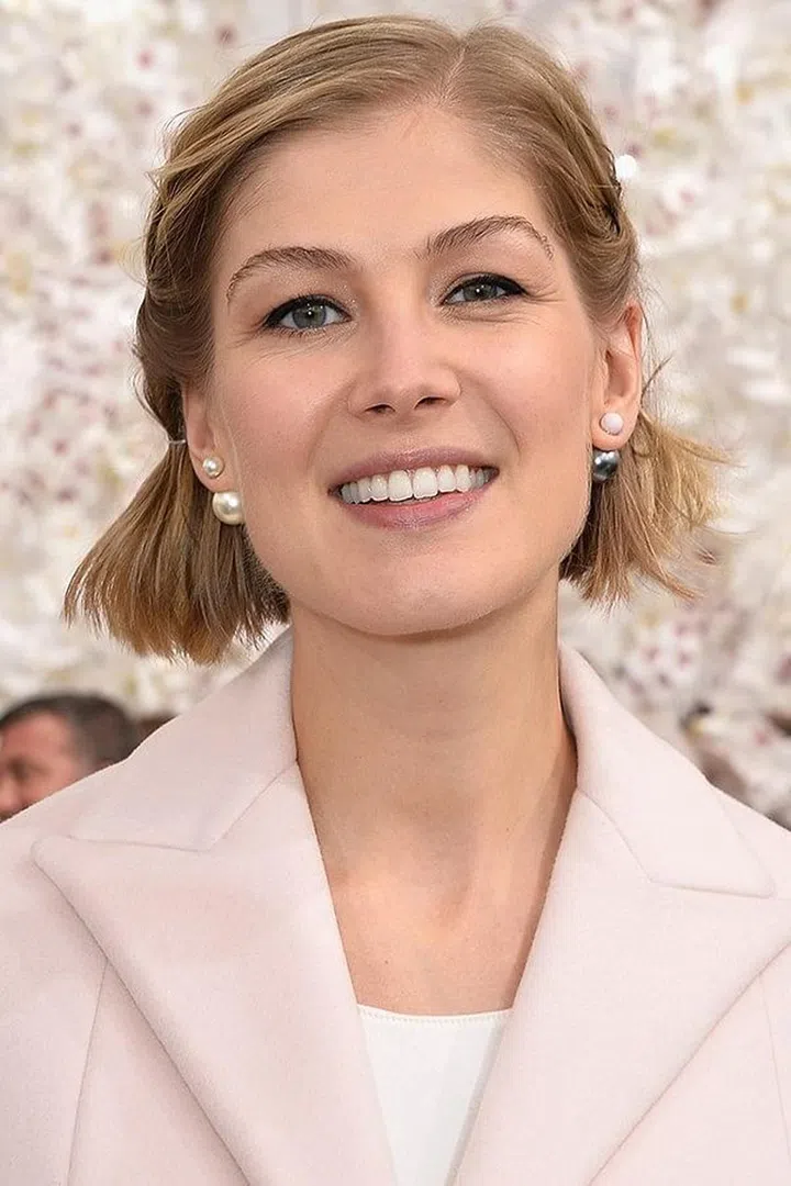 Twist and pin the front section of your hair back for a chic, preppy hair look like Rosamund Pike.