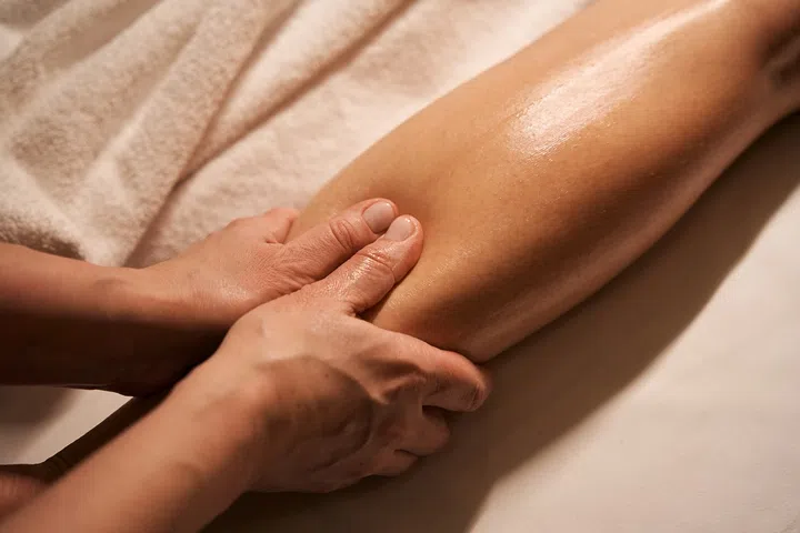 Cropped photo of experienced massotherapist hands stimulating reflex points on client lower limb