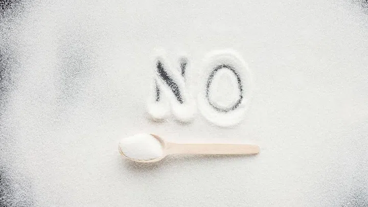 top view of handwritten word "no" on granulated sugar with wooden spoon