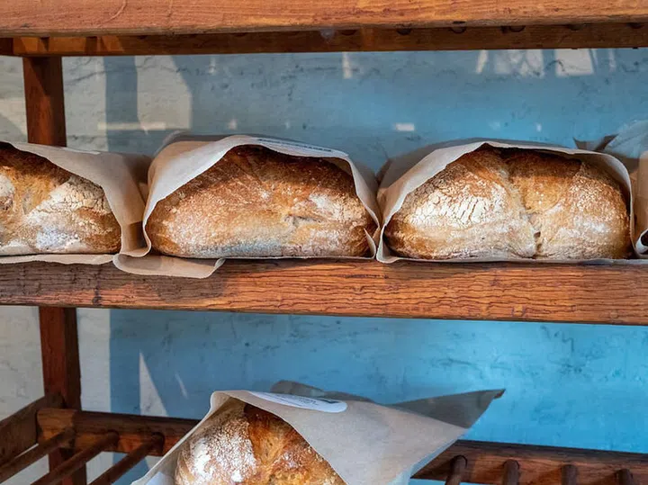 Shelf holding rows of baked and packaged loaves of bread on a bakery