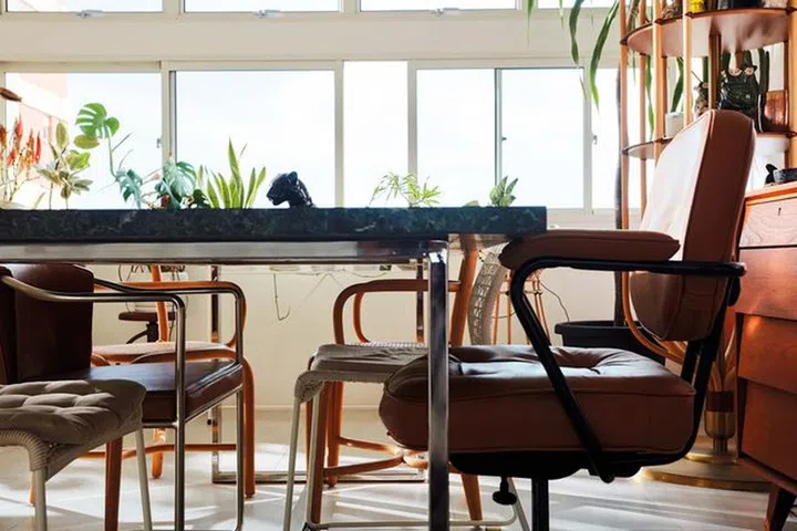 The dining area, with a striking green marble table and an assortment of chairs, mirrors Phillips’ multifaceted personality and eclectic style.Photo: Gan