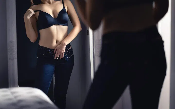 Sensual seductive sexy woman in the mirror in dark. Erotic woman wearing lingerie and underwear. Taking off bra in bedroom. Hot lady touching herself home at night. Sexual fantasy and desire.