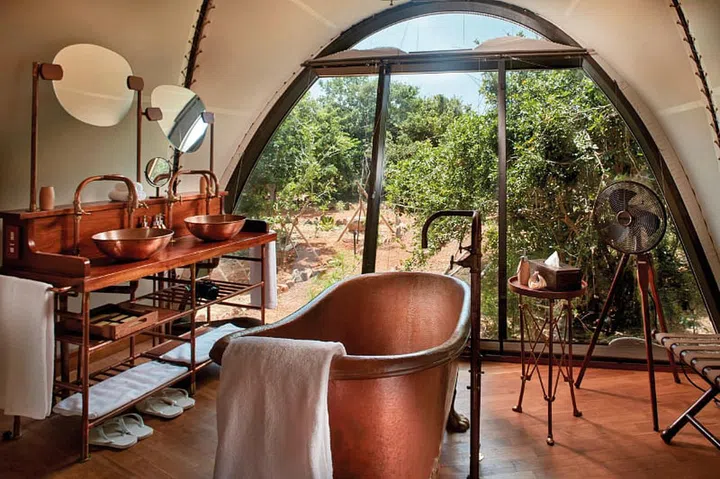 A handmade copper bathtub and repurposed metallic hardware exude colonial expedition chic.