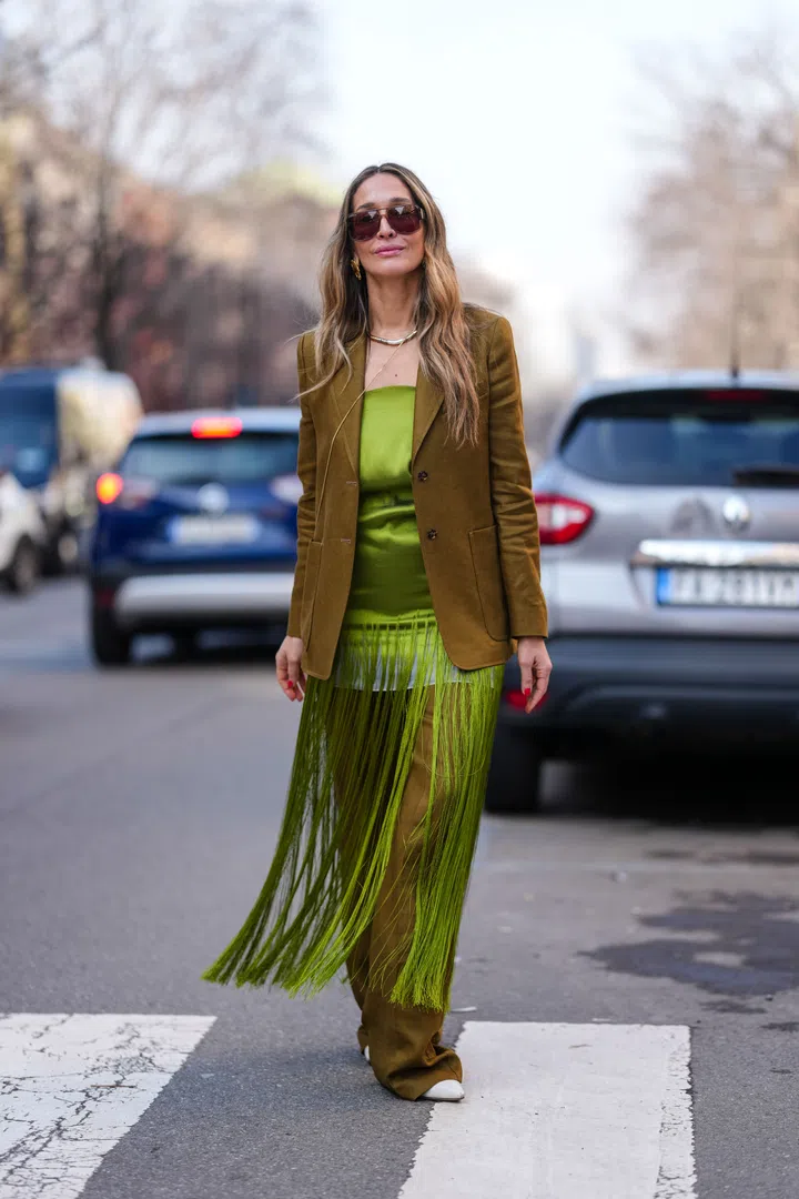 MILAN, ITALY - FEBRUARY 27: A guest wears burgundy sunglasses, gold earrings, a brown blazer jacket, a dress top with fringes, brown wide-leg pants, white leather shoes, outside Max Mara, during the Milan Fashion week Women's Fall/Winter 2025-2026 on February 27, 2025 in Milan, Italy. (Photo by Edward Berthelot/Getty Images)