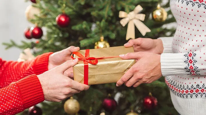 cropped shot of man presenting christmas gift to girlfriend