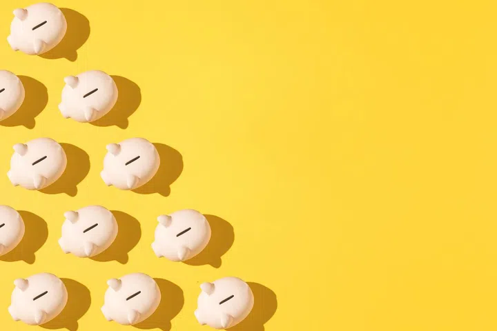 Little pink ceramic piggy bank pattern on the left side on yellow background. Concept of saving money, savings.