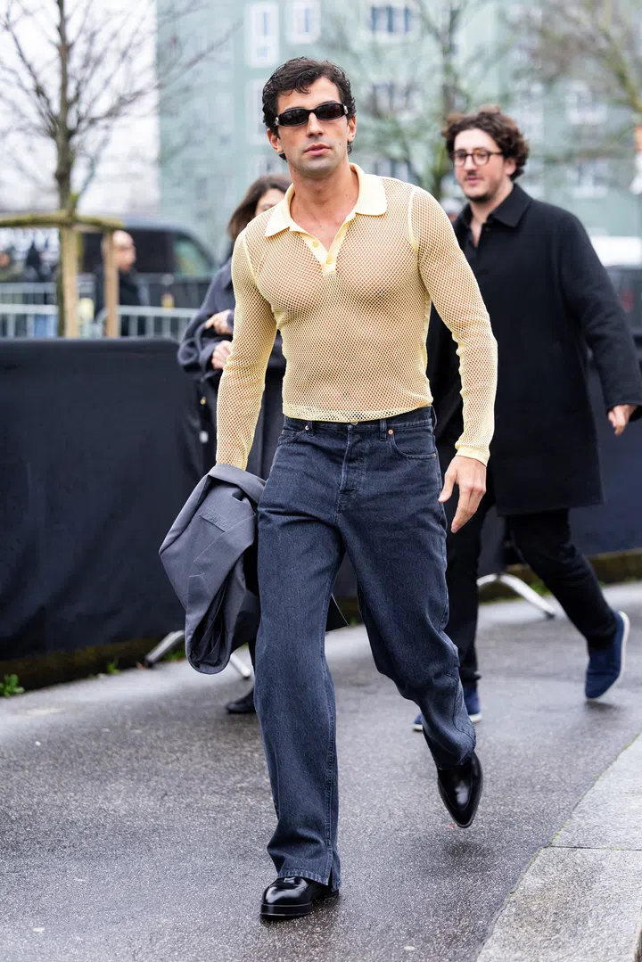 MILAN, ITALY - FEBRUARY 25: Francisco Faria wears a grey blazer, black leather loafers, black sunglasses and a yellow see-through knitted polo and grey denim trousers outside Gucci show during the Milan Fashion Week Womenswear Fall/Winter 2025/2026 on February 25, 2025 in Milan, Italy. (Photo by Valentina Frugiuele/Getty Images)