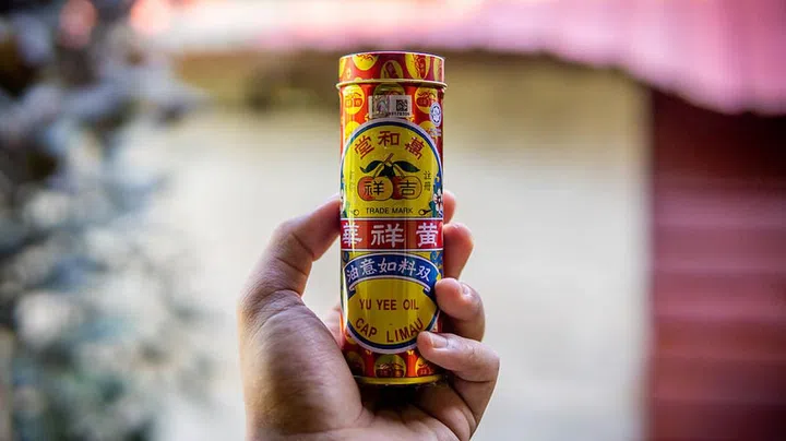 Seremban, Malaysia - December 29, 2019: Hand holding a Yu Yee Oil Cap Limau metal bottle case. It is a herbal medicated ointment used traditionally to relief winds and bloated problem.