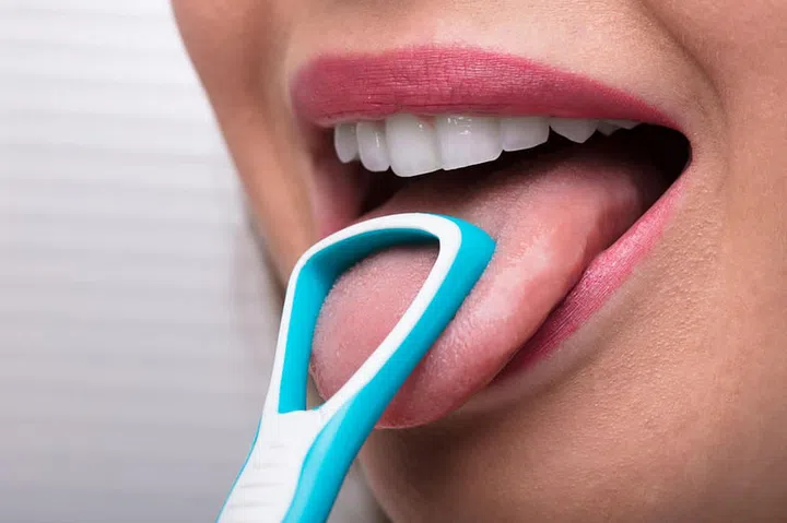 Close-up Of A Woman Cleaning Her Tongue With Cleaner