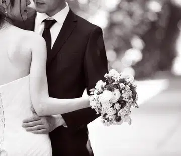 asian wedding couple hugging each other, focus on the bouquet, black and white.