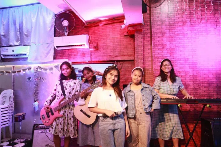 joanna hioe playing with band of youth from philippines fishing village, part of building her portfolio career cv