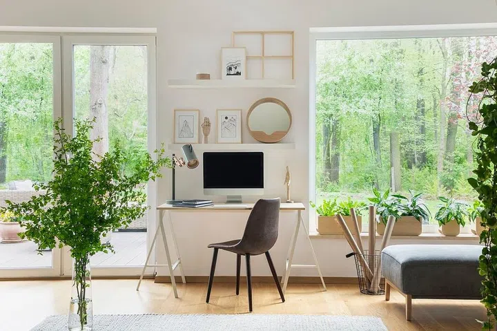 Grey chair at desk with desktop computer in scandi open space interior with windows. Real photo
