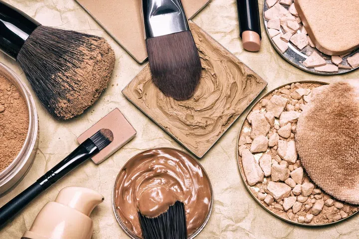 Makeup products to even skin tone and complexion on aged paper. Corrector, loose and compact powders, concealer pencil, liquid foundation with brushes and cosmetic sponges. Retro style processing