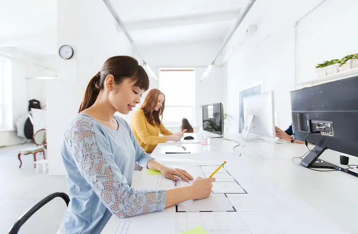 business, startup and people concept - asian architect or creative female office worker with ruler and pencil drawing on blueprint