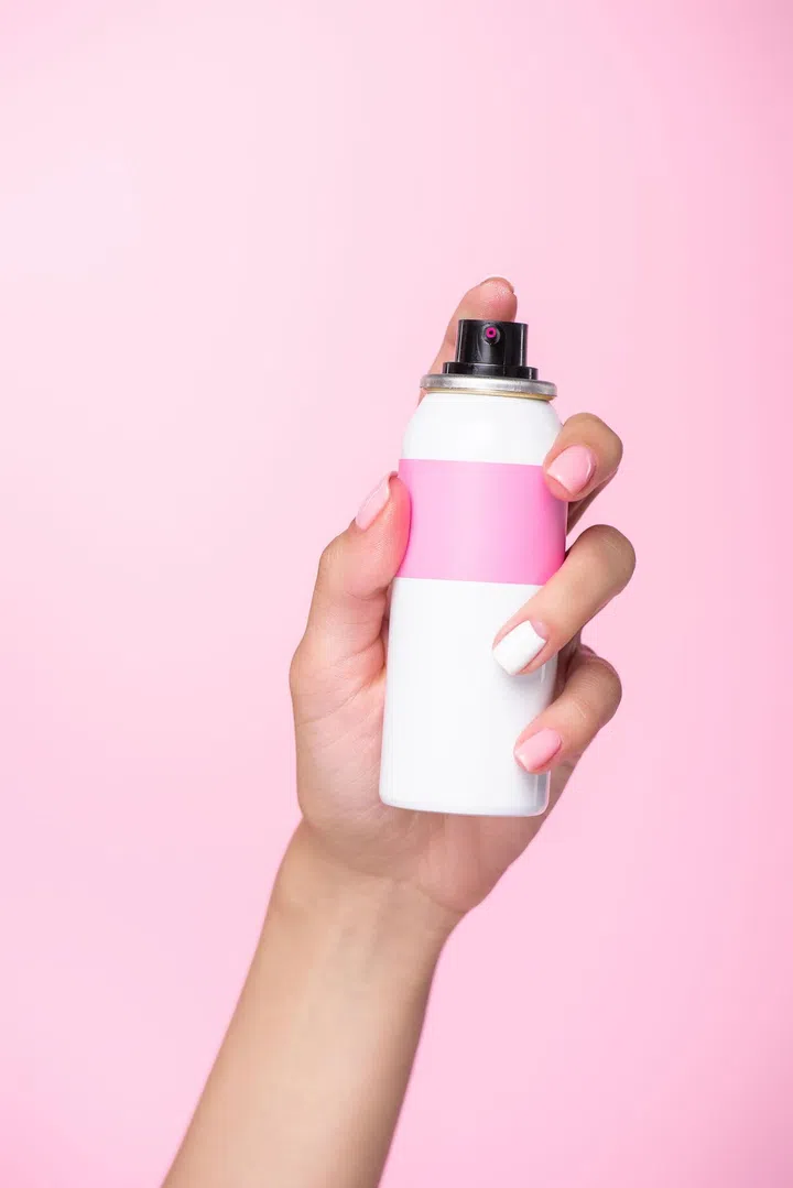 cropped shot of woman holding can of spray paint for hair isolated on pink