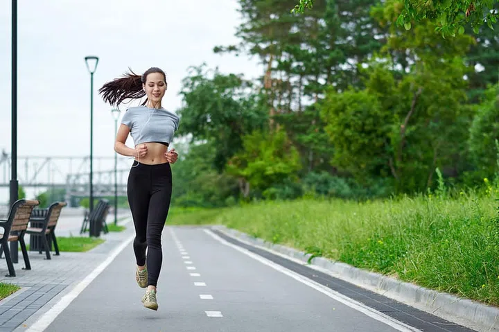 Beautiful woman running over bridge during sunset.