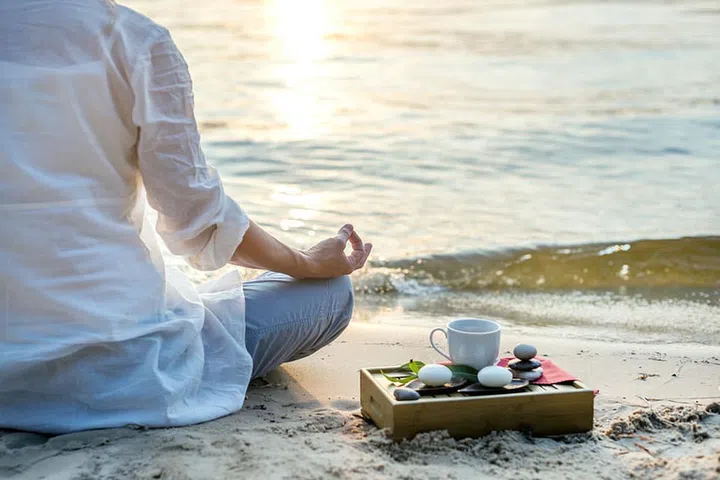 Woman meditating at the sea with tea cup