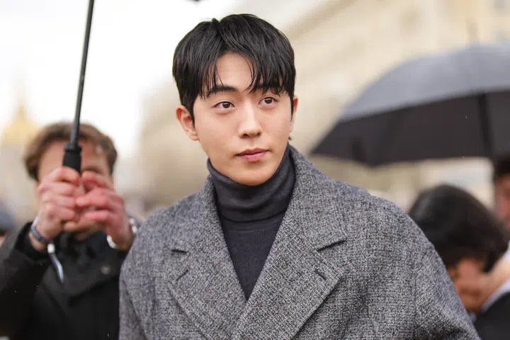 PARIS, FRANCE - JANUARY 24: Nam Joo-hyuk wears black high neck long sleeve Dior sweater, dark gray pattern double breasted cropped Dior jacket, outside Dior Homme, during the Paris Fashion week Men’s Fall/Winter 2025-2026 on January 24, 2025 in Paris, France. (Photo by Edward Berthelot/Getty Images)