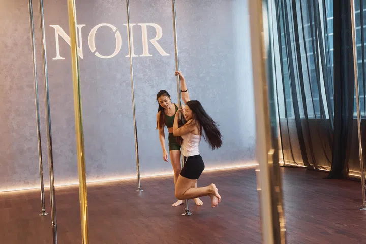 Fireman Spin: Feet are pointed, knees squeeze together against the pole, and the body’s weight is supported by the arms gripping near the top.