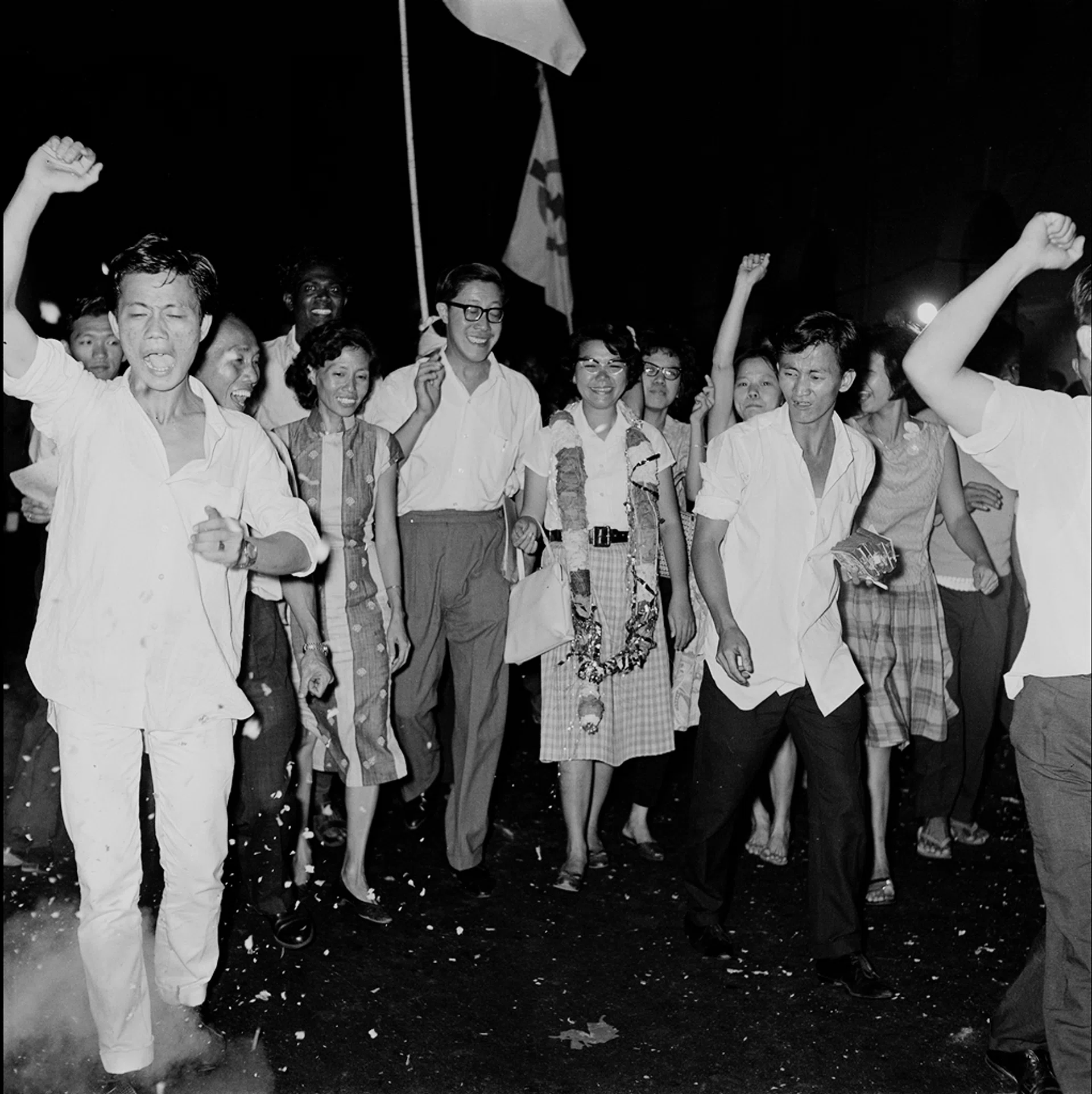 1963年，独立前最后一次选举。例打区候选人，已故陈翠嫦女士（戴花圈者，王邦文夫人）以63票险胜后，支持者热烈庆祝。 People's Action Party (PAP) candidate Chan Choy Siong (Mrs Ong Pang Boon) garlanded won in Delta. [General Elections 1963]