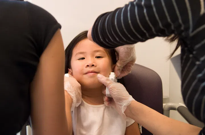 A young girl getting both of her ears pierced at the same time.