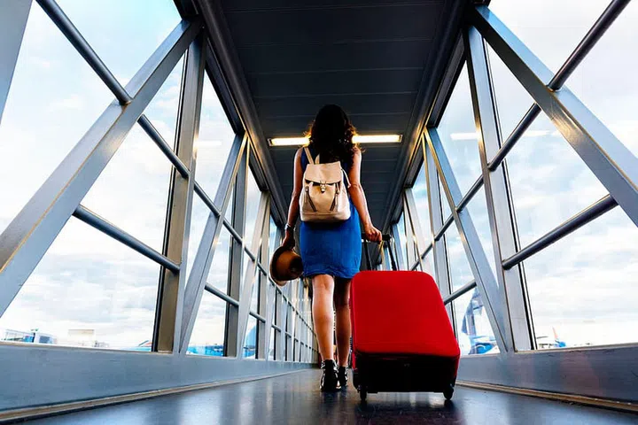Young girl traveler walking with carrying hold suitcase in the airport. Tourist Concept.