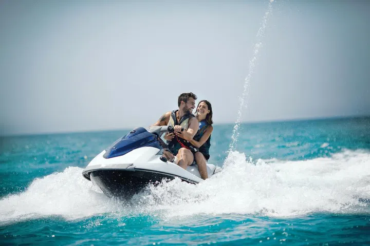 Young couple jet skiing on the open sea. They are smiling and enjoying summer sport on water.