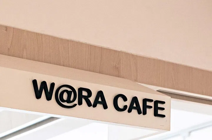 An awning built into the ceiling has a sign for the cafe’s name. The kitchen sign in a similar style ensures consistency.