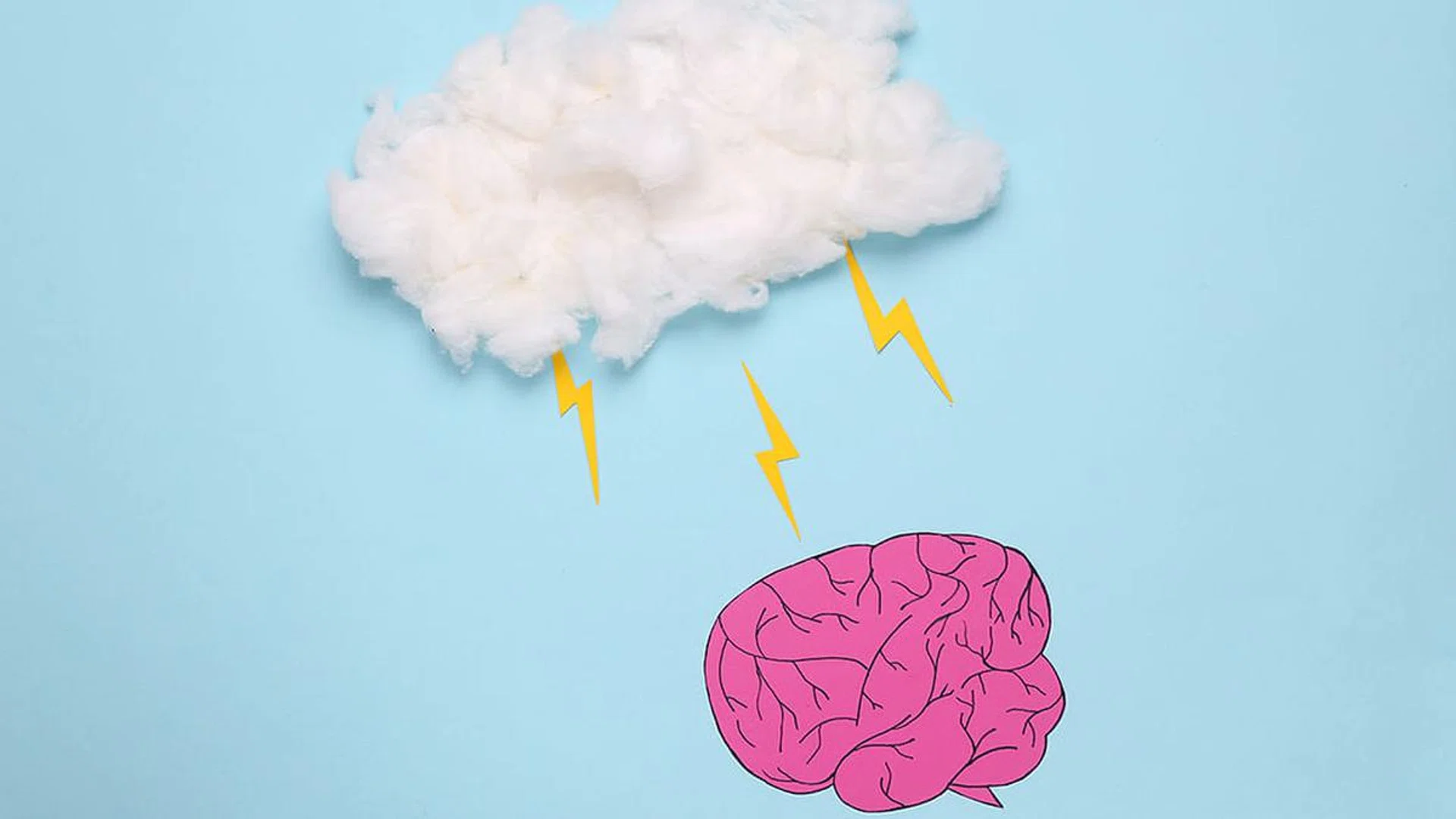 Paper-cut brain whith cloud with lightnings on a blue background. The effect of weather on well-being. Headache