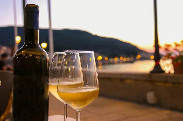 Bottle of white wine and two glasses on the restaurant table on sunset