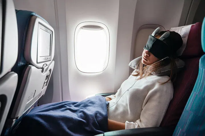 Teenage girl sleeping on boad during flight. Young passenger travelling by airplane alone.